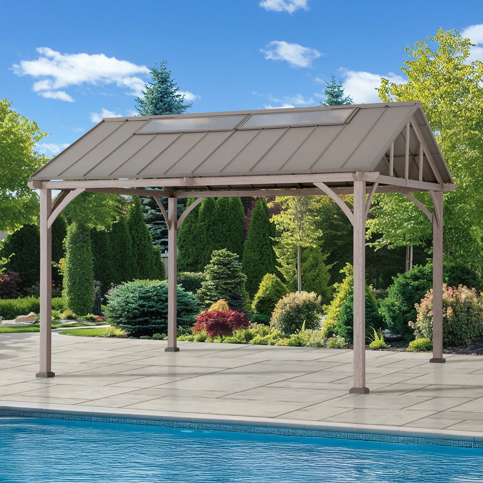 A large outdoor patio gazebo with a metal roof and wood-look steel support posts, situated on a tiled deck next to a swimming pool with a landscaped garden and blue sky in the background.